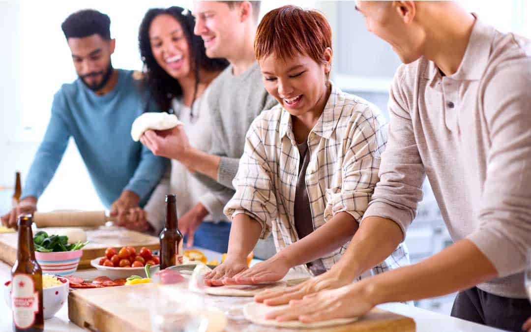event group of friends at home in kitchen making pizza