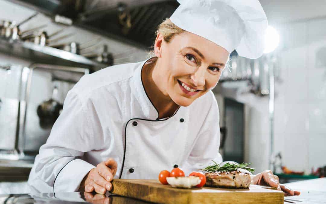 full service restaurant beautiful female chef in uniform holding meat steak